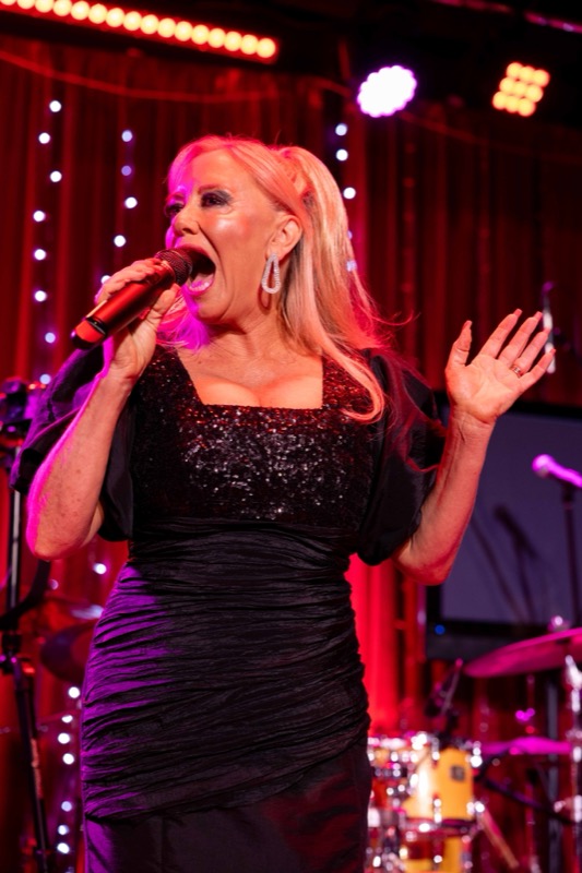 Michelle Morrison performing in a black gown on stage
