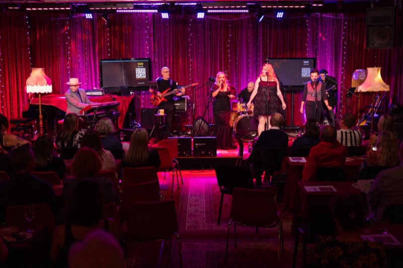 Wide shot of the band playing to a seated audience