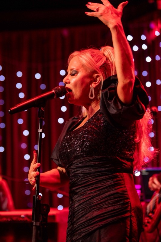 Michelle Morrison singing with her arm raised